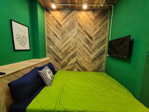 a green room with a bed with a wooden wall at Lightning House in Da Lat