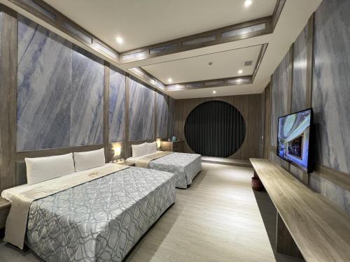 a bedroom with two beds and a flat screen tv at 亞曼尼汽車旅館-頭份館 in Toufen