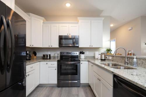 a kitchen with white cabinets and black appliances at Modern 4BR Ground Level King Beds Steps 2 Beach C in Myrtle Beach