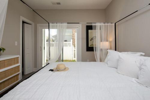 a bedroom with a large white bed with a hat on it at Modern 4BR Ground Level King Beds Steps 2 Beach C in Myrtle Beach