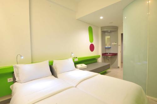 فندق بوب! ديبونيغورو في سورابايا: غرفة نوم بسرير ابيض وجدار اخضر