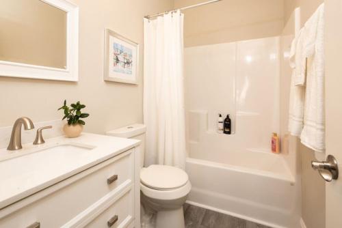 a white bathroom with a toilet and a shower at Modern 4BR Ground Level King Beds Steps 2 Beach C in Myrtle Beach
