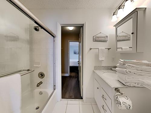 a white bathroom with a shower and a sink at Villas on the Gulf #H6 in Pensacola Beach