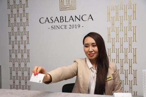 a woman sitting at a table holding a piece of paper at Casablanca Apart Hotel in Bishkek
