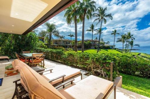 an outdoor patio with a table and chairs and the ocean at MAKENA SURF, #G-101 condo in Wailea
