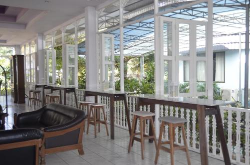 a restaurant with tables and stools and windows at Silversand Villa Hotel in Jomtien Beach