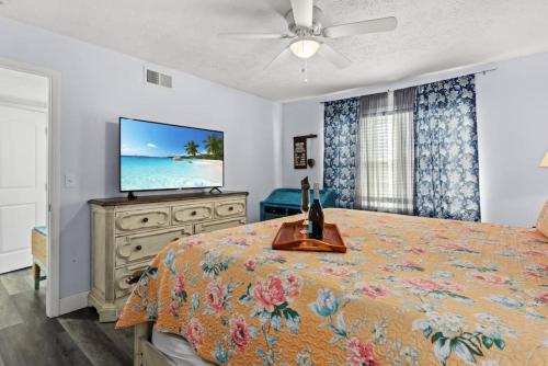 a bedroom with a bed and a flat screen tv at Seaside Serenity at Shiplap Shack, Updated Coastal Beach Home w Beach Gear and Idyllic Outdoor Living, Just Steps from the Shore in Panama City Beach