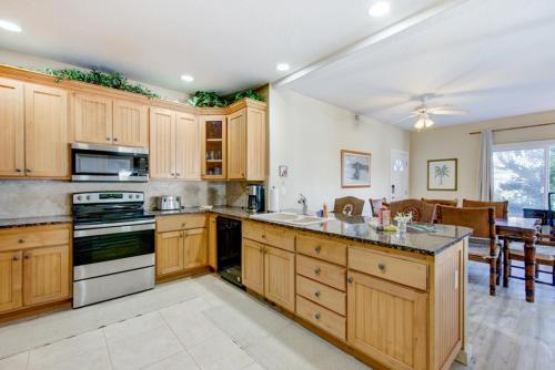 a large kitchen with wooden cabinets and a dining room at Kauai Regency at Poipu Kai by Coldwell Banker Island Rentals in Koloa