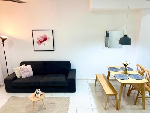 a living room with a black couch and a table at Melur Homestay in Setia Alam