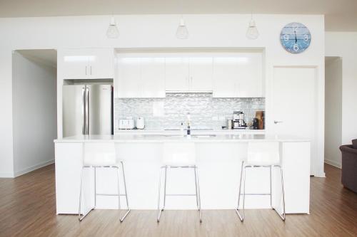 a white kitchen with a large white counter and stools at TWO PELICANS Island Beach in Island Beach
