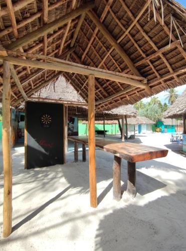 a wooden picnic table under a roof on the beach at Princess of Zanzibar in Michamvi