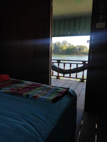 a bed in a room with a view of the water at Mr. Phaos Riverview Guesthouse & Restaurant in Don Det