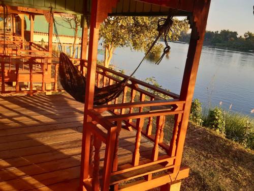 a hammock on a deck next to a lake at Mr. Phaos Riverview Guesthouse & Restaurant in Don Det
