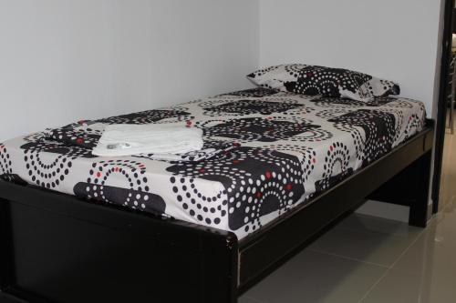 a bed with a black and white comforter and pillows at CASA ESTADIO MEDELLIN ! Apartamentos RENOVADOS en EXCELENTE UBICACION Laureles Estadio in Medellín