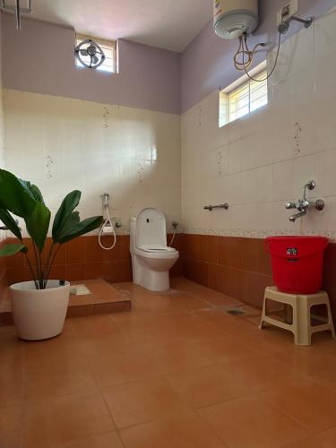 a bathroom with a toilet and a potted plant at Rustic Village Farmhouse in Bangalore