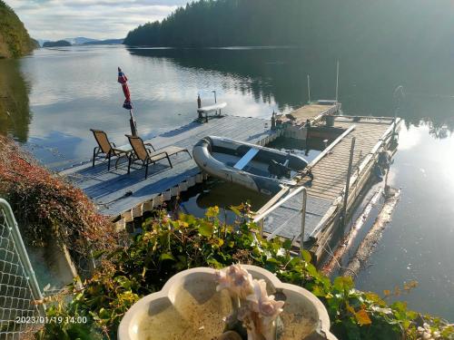 a dock with a boat and chairs on the water at luxury ocean dock pool villa in Ladysmith