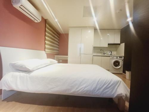 a bedroom with a white bed and a kitchen at Olive hostel R(Residence) in Seoul