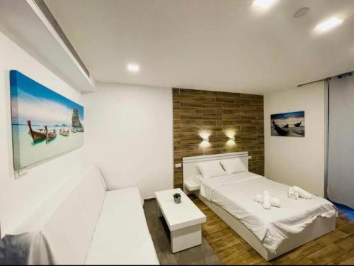 a white bedroom with a bed and a table at BRiGHT AND COZY STUDIO SUiTE EiLAT in Eilat