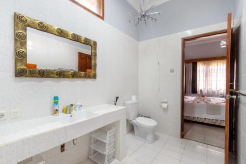 a bathroom with a sink and a toilet and a mirror at Bon Nyuh Bungalows in Gianyar