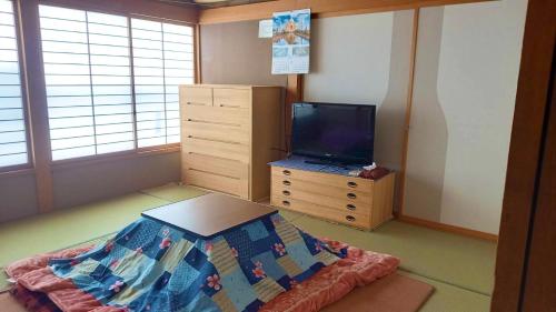 a bedroom with a bed and a tv on a dresser at Bandai in Tokamachi
