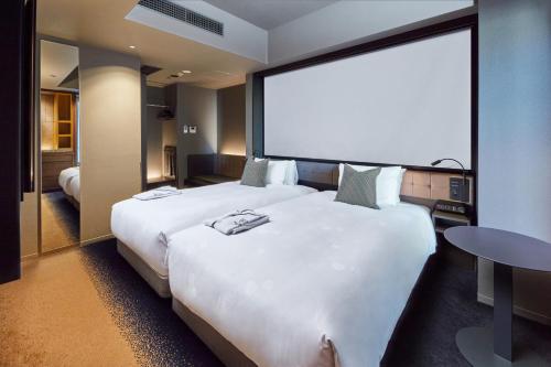 a large white bed in a hotel room with a large screen at The Royal Park Canvas - Ginza 8 in Tokyo