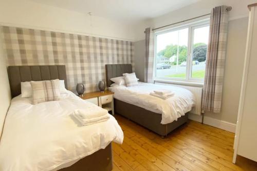 two beds in a room with a window at Meadowside Troutbeck Bridge, Windermere sleeps 5-6 in Windermere
