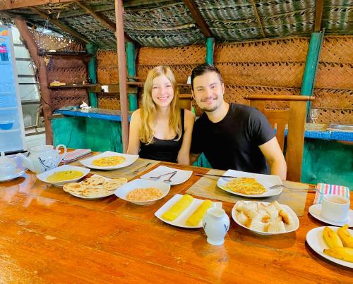 un hombre y una mujer sentados en una mesa con comida en Sheran Safari House en Udawalawe