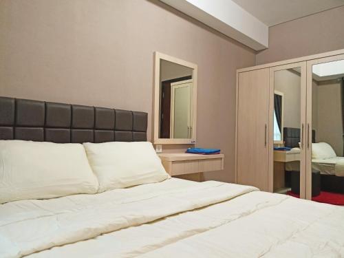 バリクパパンにあるApartement Borneo Bay Tower kartanegara Balikpapanのベッドルーム1室(大型ベッド1台、鏡2つ付)