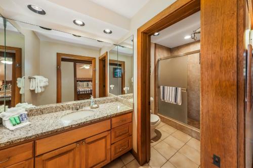 a bathroom with a sink and a toilet and a mirror at Kauai Kiahuna Plantation by Coldwell Banker Island Vacations in Koloa