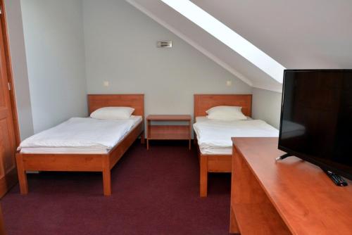 a room with two beds and a flat screen tv at Belvárosi Vendégház in Mór
