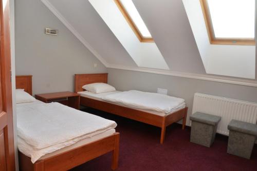 a attic room with two beds and a window at Belvárosi Vendégház in Mór