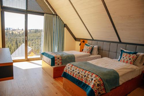 two beds in a room with a large window at SKOGUR - Home & Resort in Bukovel