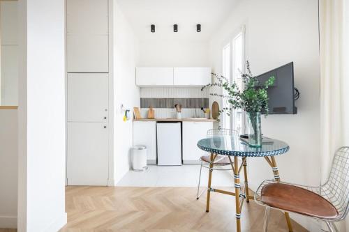 une cuisine blanche avec une table et des chaises en verre dans l'établissement Nau, à Marseille