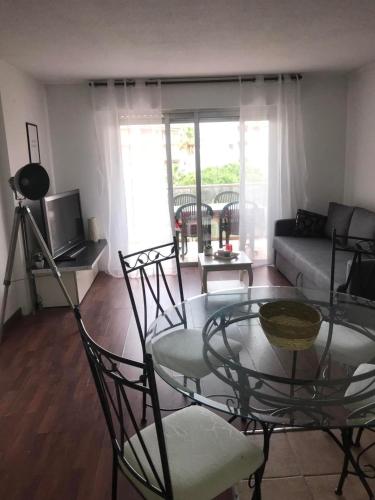 un salon avec une table en verre et des chaises dans l'établissement Appartement en front de mer avec parking privatif, à Fréjus