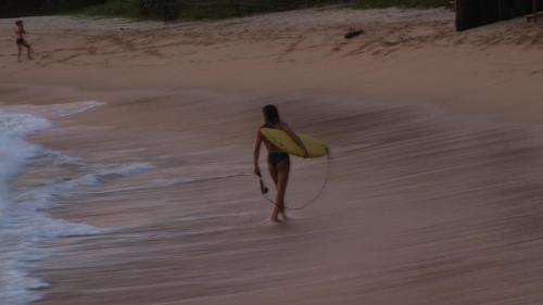 a woman walking on the beach with a surfboard at South Sea Villa in Midigama