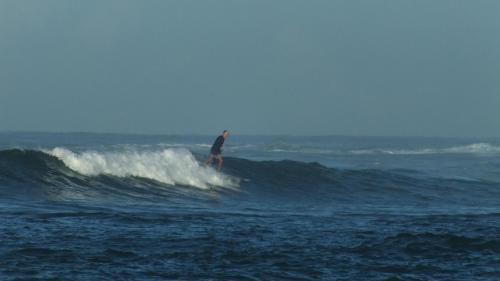 a man riding a wave on a surfboard in the ocean at South Sea Villa in Midigama