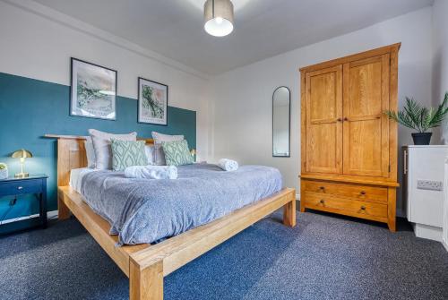 1 dormitorio con 1 cama y armario de madera en Brewery Loft - 3 Bedroom Bright Spacious apartment in the centre of town, Wifi, Netflix, en Cirencester