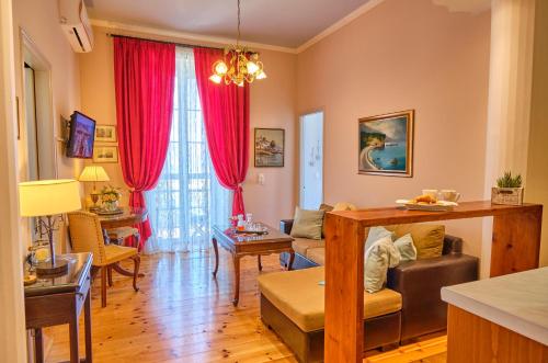 a living room with red curtains and a couch and a table at Anesis Apartment Corfu Town in Corfu
