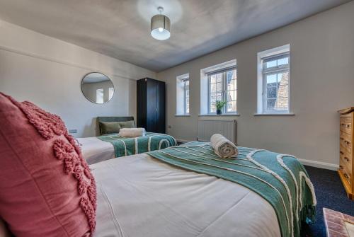 a bedroom with two beds and two windows at Brewery Loft - 3 Bedroom Bright Spacious apartment in the centre of town, Wifi, Netflix in Cirencester