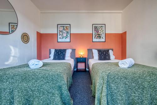 two beds in a room with orange and white walls at Brewery Loft - 3 Bedroom Bright Spacious apartment in the centre of town, Wifi, Netflix in Cirencester