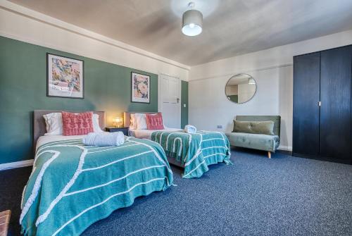 Habitación con 2 camas, sofá y silla en Brewery Loft - 3 Bedroom Bright Spacious apartment in the centre of town, Wifi, Netflix, en Cirencester