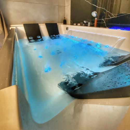 a bath tub with blue water in it at Apartament z jacuzzi in Krakow
