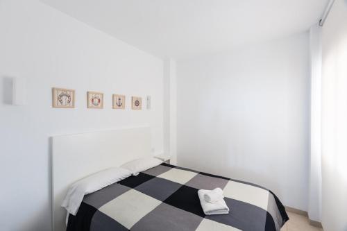 a white room with a bed with a black and white blanket at Las Dunas 02 in Denia