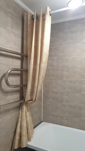 a shower with a curtain in a bathroom at 1-комнатная квартира in Kokshetau