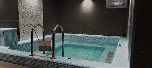 een groot zwembad met blauwe tegels in de badkamer bij Hotel Szeifert in Sovata