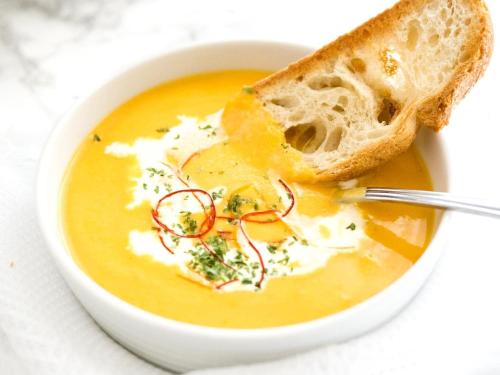 a bowl of soup with a piece of bread at Pohorje Village Wellbeing Resort - Family Apartments Bolfenk in Pohorje