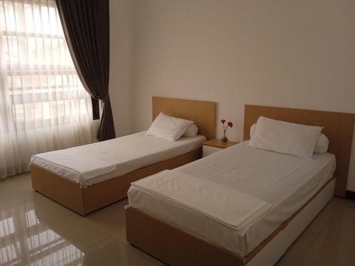 two beds in a hotel room with a window at New 3br The Green Home in Kepiting-kidul