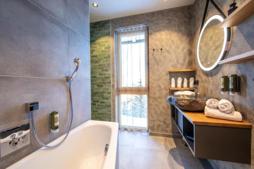 a bathroom with a tub and a sink and a mirror at Höflehner Premium Eco Lodge in Haus im Ennstal