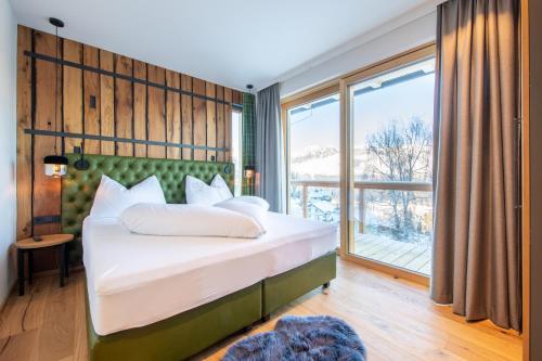 - une chambre avec un lit et une grande fenêtre dans l'établissement Höflehner Premium Eco Lodge, à Haus im Ennstal