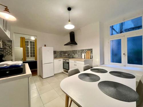 Il comprend une cuisine équipée d'une table blanche et d'un réfrigérateur blanc. dans l'établissement Appartement confort - Carcassonne centre, à Carcassonne